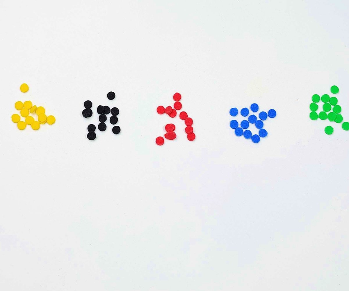 Toilet Paper Craft- Step 1-Hole punched dots on a white background yellow, black, red, blue, and green -Kids Activities blog