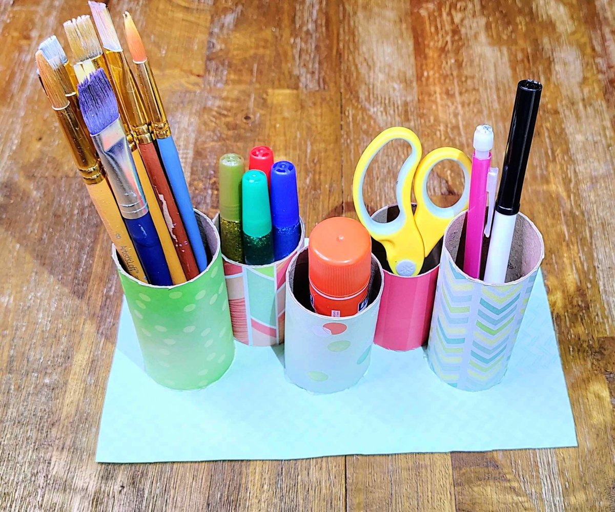 Toilet Paper Roll Craft- art supply organizer on a wooden table with pencil, marker, scissors, glue, glitter, and paintbrushes- kids activities blog