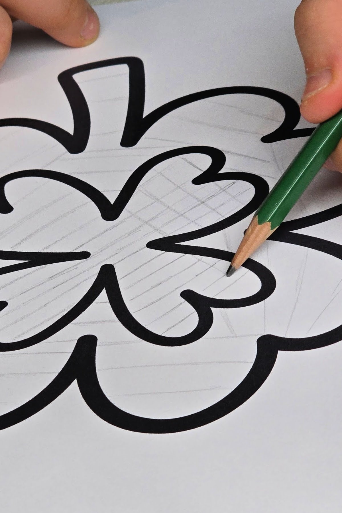 step 1 - boy using a pencil to sketch a zentangle design on a shamrock coloring page - kids activities blog