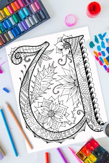 Zentangle alphabet coloring pages - letter u zentangle design on background of paint, colored pencils and art supplies
